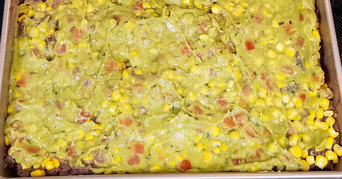 Layered Tex Mex Casserole layer of guacamole added to baking pan